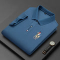 Blue polo shirt with embroidered polo player, folded next to a black wristwatch.