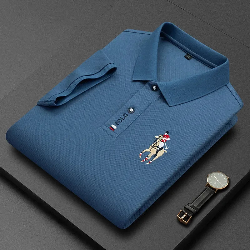 Blue polo shirt with embroidered polo player, folded next to a black wristwatch.