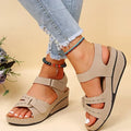 Beige comfort wedge sandals for women with velcro straps, worn with frayed jeans.